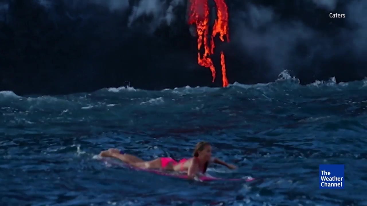 Surfer Paddles Close to Hawaiian Lava